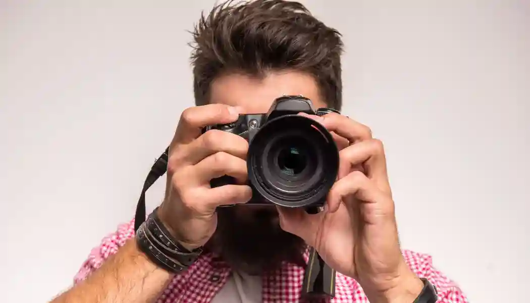 Foto de un fotografo apuntando con una camara en primer plano.