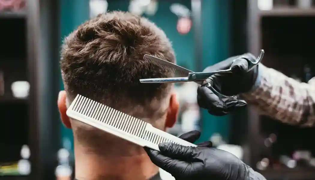 Foto de una barbeía donde un barbero le esta cortando el pelo a un cliente.