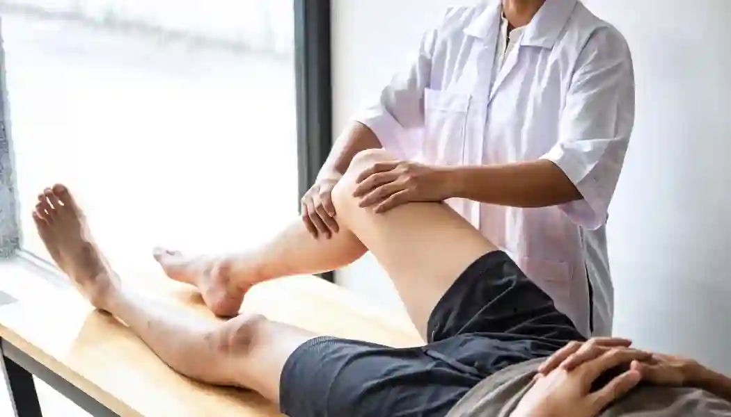 Foto de un paciente en una camilla siendo tratado por un fisioterapeuta.